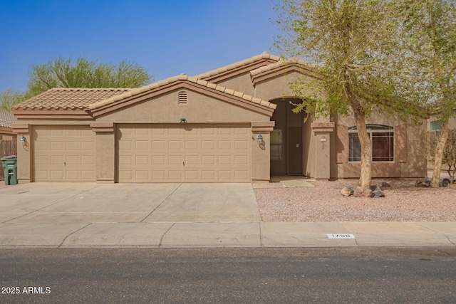 view of front of home featuring driveway, a tile roof, a garage, and stucco siding