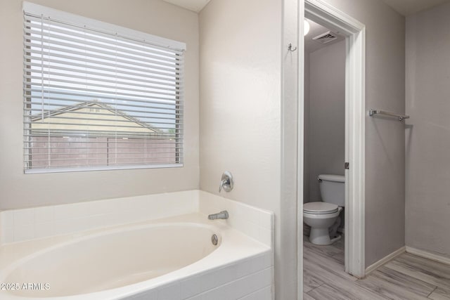 full bath featuring visible vents, toilet, wood finished floors, and a bath