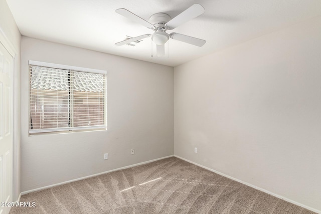 carpeted spare room with a ceiling fan and baseboards