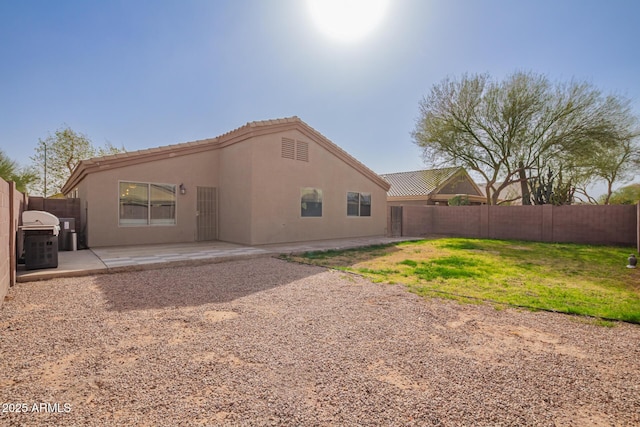 back of house featuring a lawn, a fenced backyard, a tiled roof, a patio area, and stucco siding