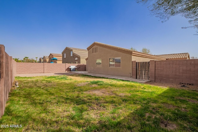 back of house with a yard, a fenced backyard, and stucco siding