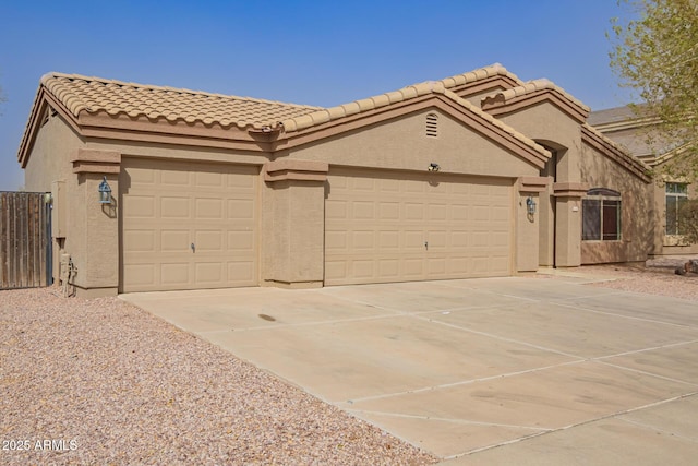 view of front of house featuring a garage, driveway, a tile roof, and stucco siding