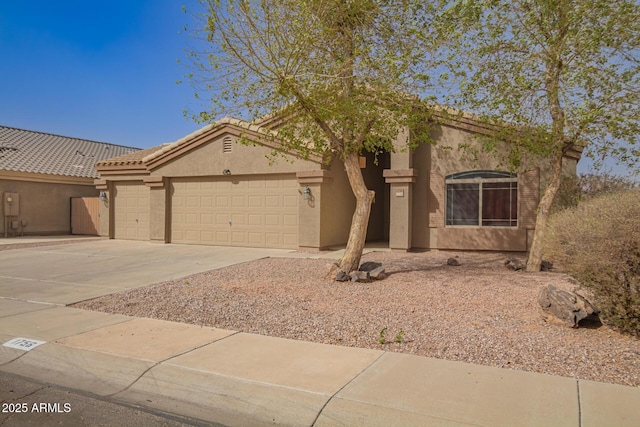 view of front of house featuring a garage, driveway, a tiled roof, and stucco siding