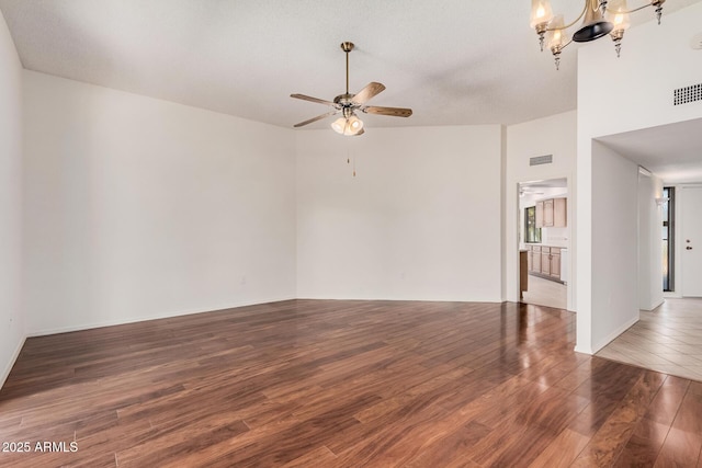 spare room with dark hardwood / wood-style flooring and ceiling fan with notable chandelier