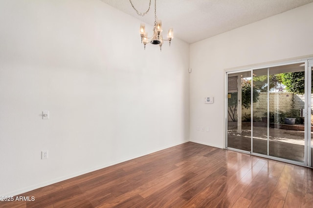 unfurnished room with an inviting chandelier and hardwood / wood-style floors