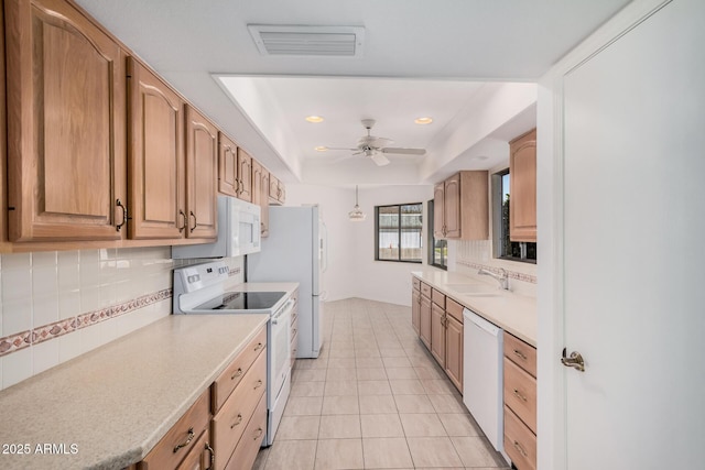 kitchen featuring sink, light tile patterned floors, a raised ceiling, white appliances, and backsplash