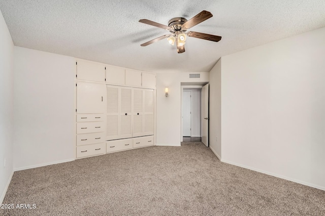 unfurnished bedroom featuring ceiling fan, a closet, light carpet, and a textured ceiling