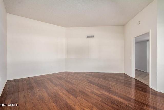 unfurnished room with hardwood / wood-style flooring and a textured ceiling