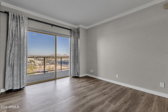 spare room featuring wood-type flooring and ornamental molding