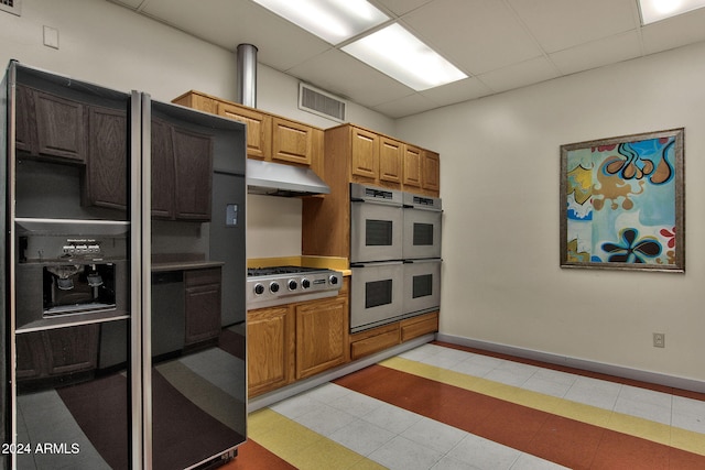 kitchen featuring a paneled ceiling, stainless steel gas stovetop, white double oven, and black refrigerator with ice dispenser