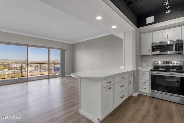 kitchen with kitchen peninsula, white cabinetry, hardwood / wood-style floors, and appliances with stainless steel finishes