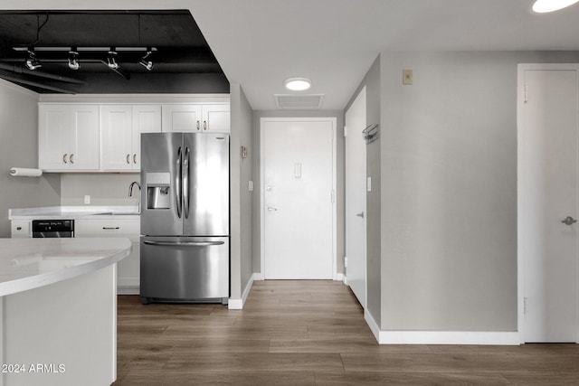 kitchen with light stone countertops, appliances with stainless steel finishes, hardwood / wood-style flooring, and white cabinetry