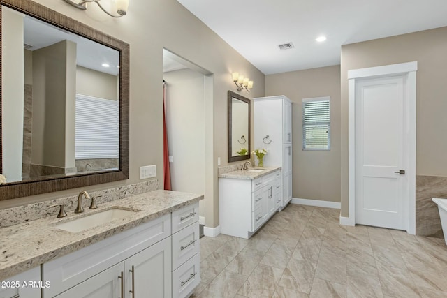 bathroom with two vanities, a sink, visible vents, and baseboards