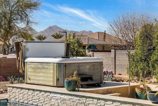 view of patio featuring fence, a mountain view, and a hot tub