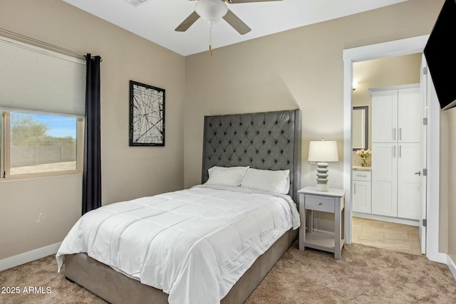 bedroom featuring ceiling fan, baseboards, connected bathroom, and light colored carpet