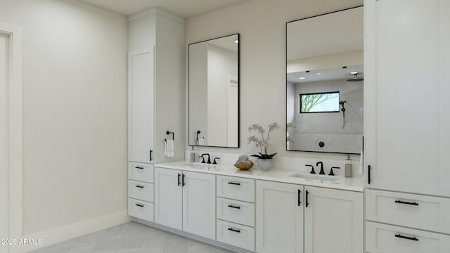 bathroom featuring tiled shower, a sink, baseboards, and double vanity