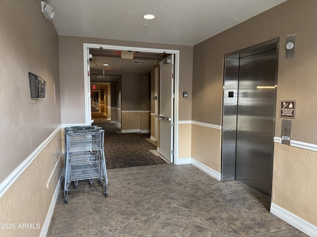 corridor with elevator and baseboards