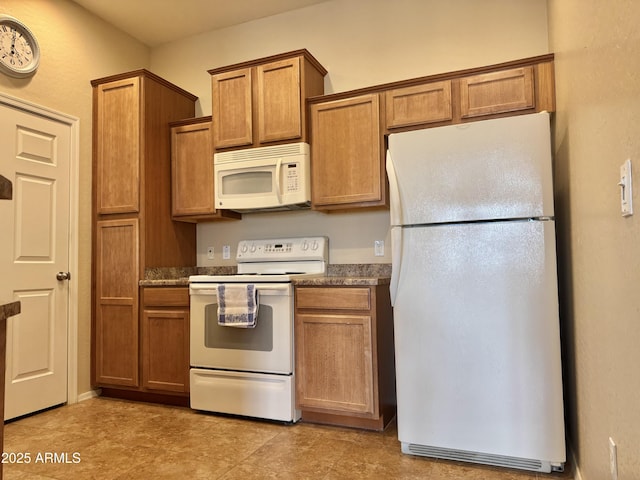 kitchen featuring white appliances, brown cabinetry, and dark countertops