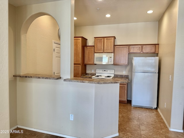 kitchen featuring white appliances, baseboards, brown cabinetry, and recessed lighting