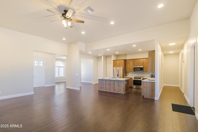 kitchen with ceiling fan, stainless steel appliances, dark hardwood / wood-style floors, tasteful backsplash, and an island with sink