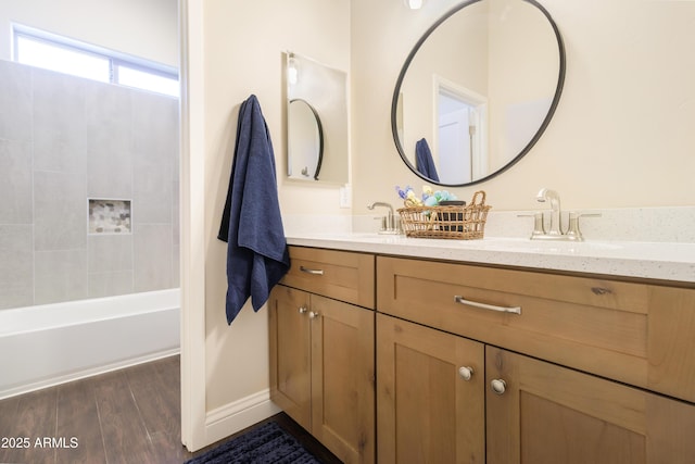 bathroom with wood-type flooring, tiled shower / bath combo, and vanity