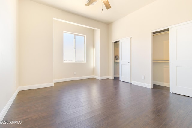 unfurnished bedroom featuring two closets, dark hardwood / wood-style floors, and ceiling fan