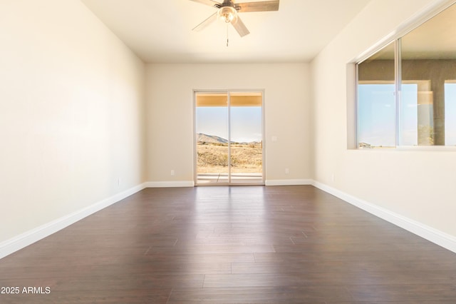 unfurnished room with dark wood-type flooring, ceiling fan, and a mountain view