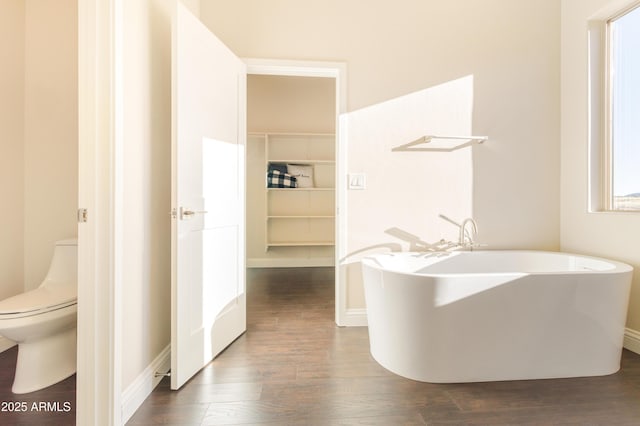 bathroom featuring hardwood / wood-style floors, a bath, and toilet