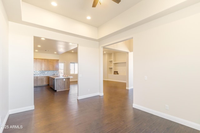 unfurnished living room featuring dark wood-type flooring, built in features, and ceiling fan