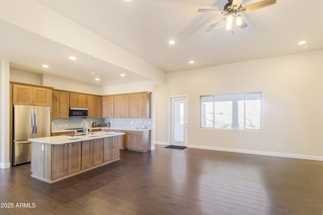 kitchen featuring tasteful backsplash, dark hardwood / wood-style flooring, stainless steel appliances, and a center island with sink