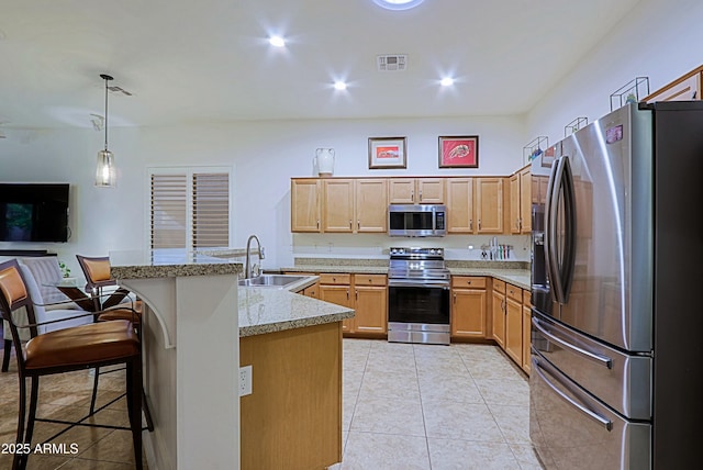 kitchen with visible vents, a breakfast bar, a sink, and stainless steel appliances