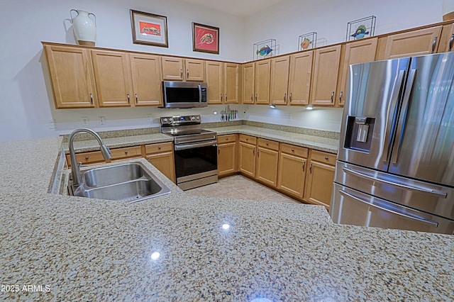 kitchen featuring light tile patterned floors, a sink, appliances with stainless steel finishes, and light stone counters