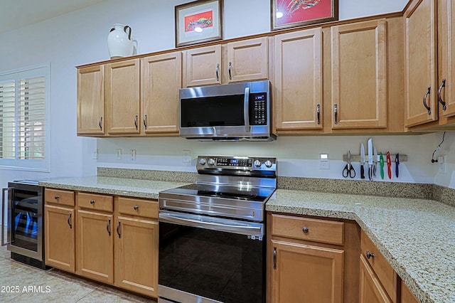 kitchen with beverage cooler, light stone countertops, appliances with stainless steel finishes, and light brown cabinets