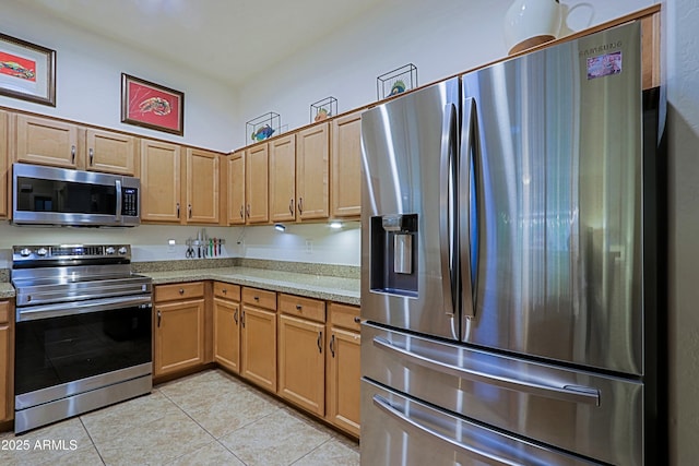 kitchen featuring light stone counters, light tile patterned floors, and appliances with stainless steel finishes