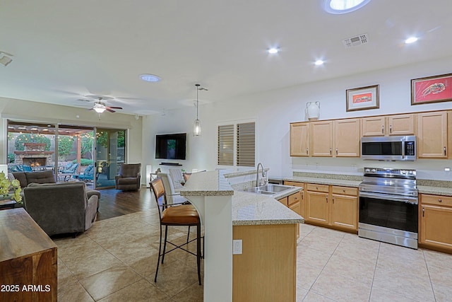 kitchen featuring open floor plan, a breakfast bar area, stainless steel appliances, a sink, and visible vents