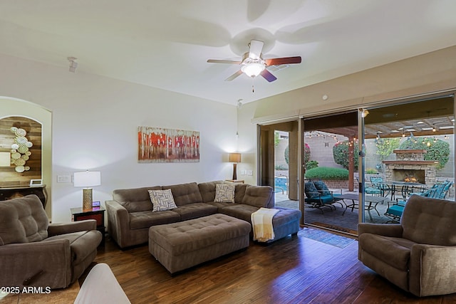 living area featuring a stone fireplace, wood finished floors, and ceiling fan