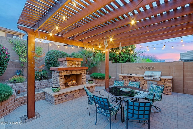 view of patio / terrace with an outdoor kitchen, a fenced backyard, an outdoor stone fireplace, grilling area, and outdoor dining area