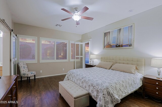 bedroom featuring baseboards, a barn door, visible vents, ceiling fan, and wood finished floors