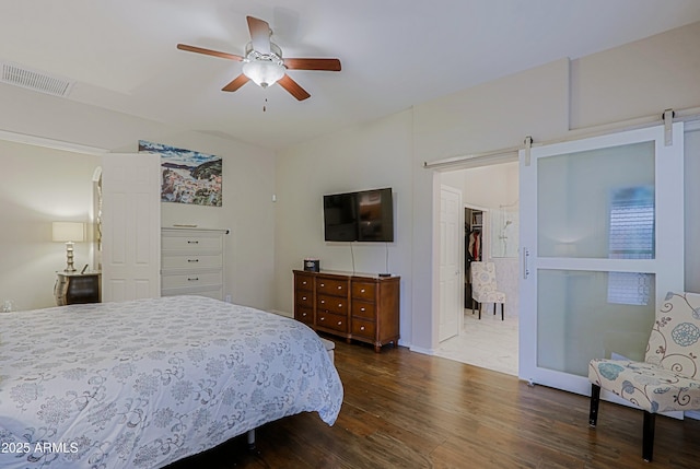 bedroom with a barn door, visible vents, and dark wood-style flooring
