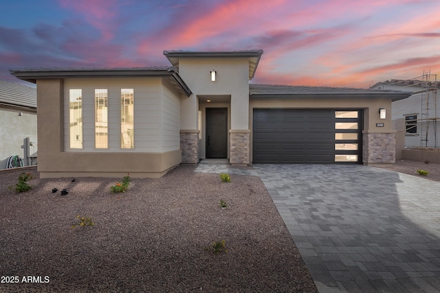 21411 W Meadowbrook Ave, Buckeye, AZ 85396 - view of front of house featuring a garage, decorative driveway, stone siding, and stucco siding