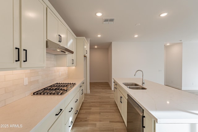 21411 W Meadowbrook Ave, Buckeye, AZ 85396 - kitchen featuring stainless steel appliances, under cabinet range hood, light stone countertops, light wood-style floors, and tasteful backsplash