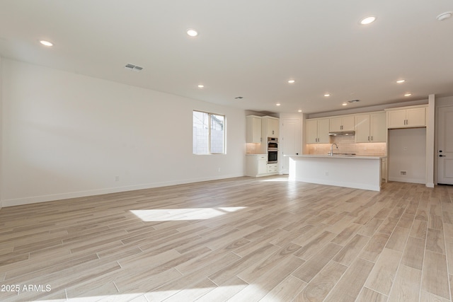 21411 W Meadowbrook Ave, Buckeye, AZ 85396 - unfurnished living room with light wood finished floors and recessed lighting