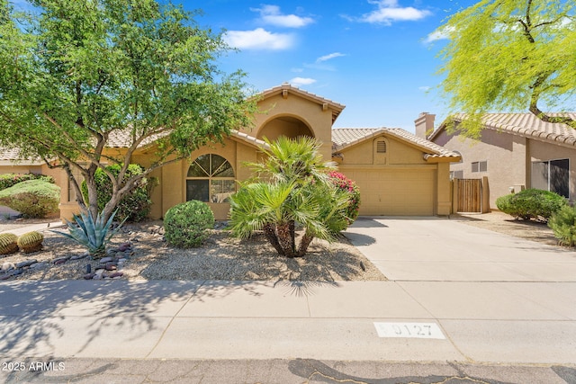 mediterranean / spanish-style home with stucco siding, an attached garage, driveway, a tiled roof, and fence
