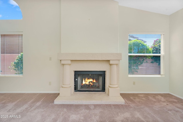 detailed view of a lit fireplace, carpet, and baseboards