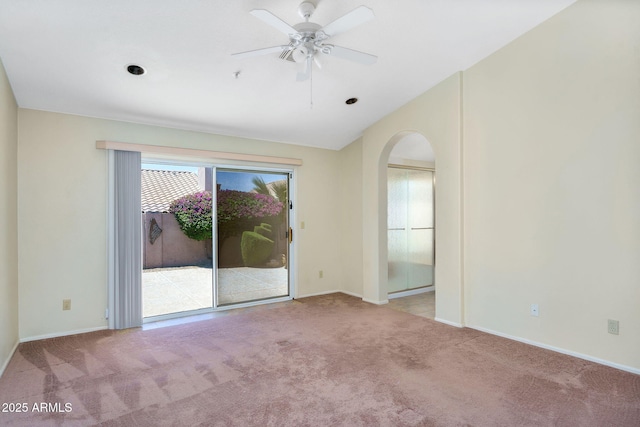spare room featuring arched walkways, carpet, vaulted ceiling, baseboards, and ceiling fan
