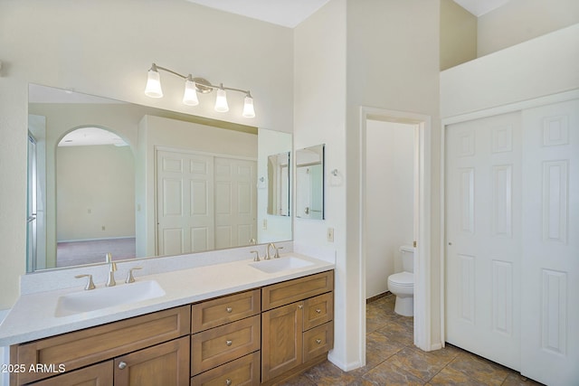 bathroom featuring toilet, double vanity, and baseboards