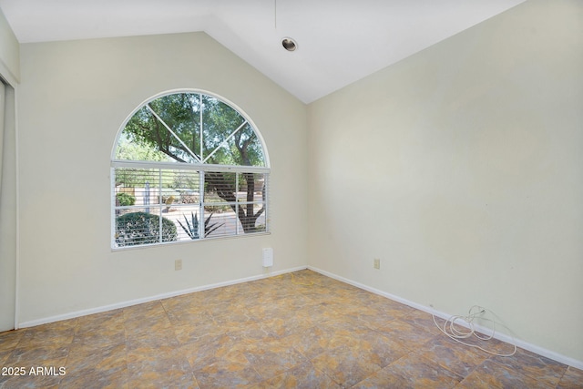 spare room with vaulted ceiling and stone finish flooring