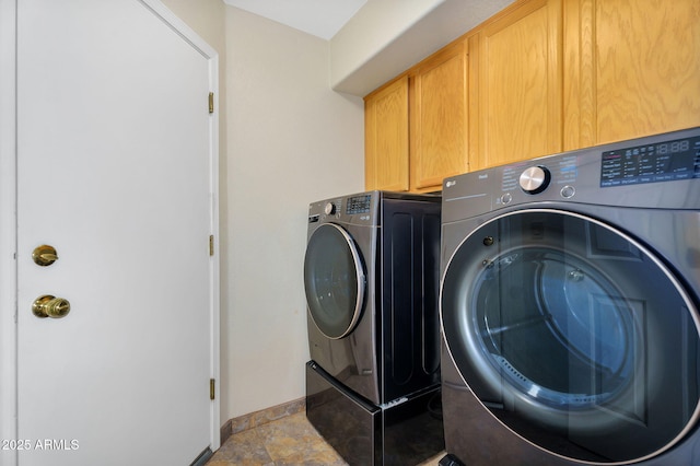 laundry room with cabinet space, washing machine and dryer, baseboards, and stone finish floors