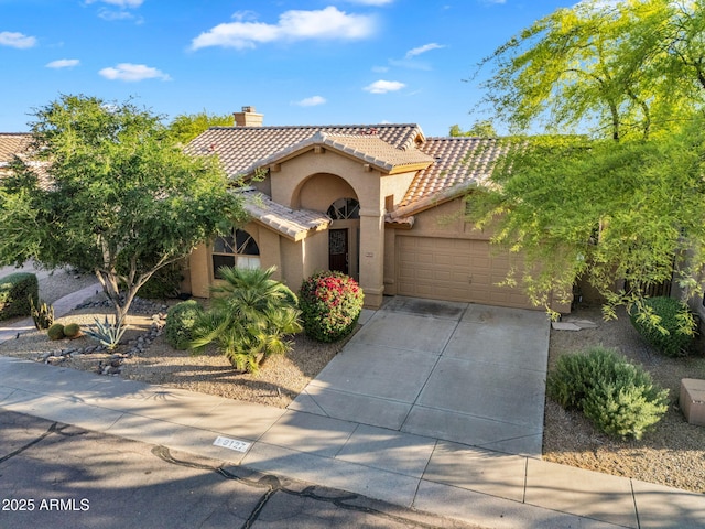 mediterranean / spanish house featuring a tiled roof, stucco siding, a chimney, an attached garage, and concrete driveway