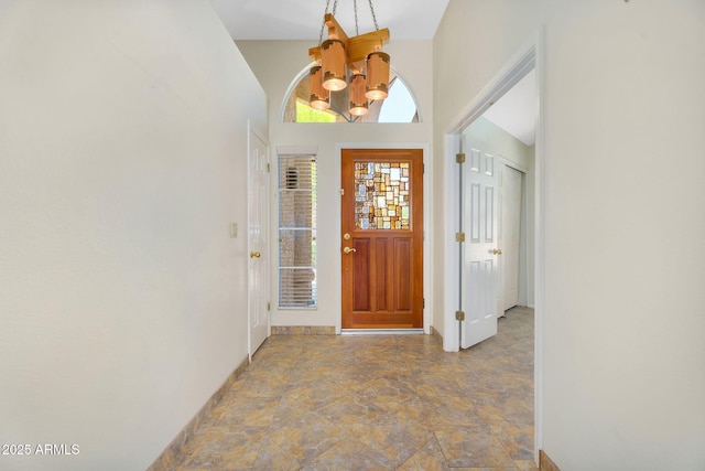 foyer entrance featuring a chandelier, stone finish flooring, and baseboards